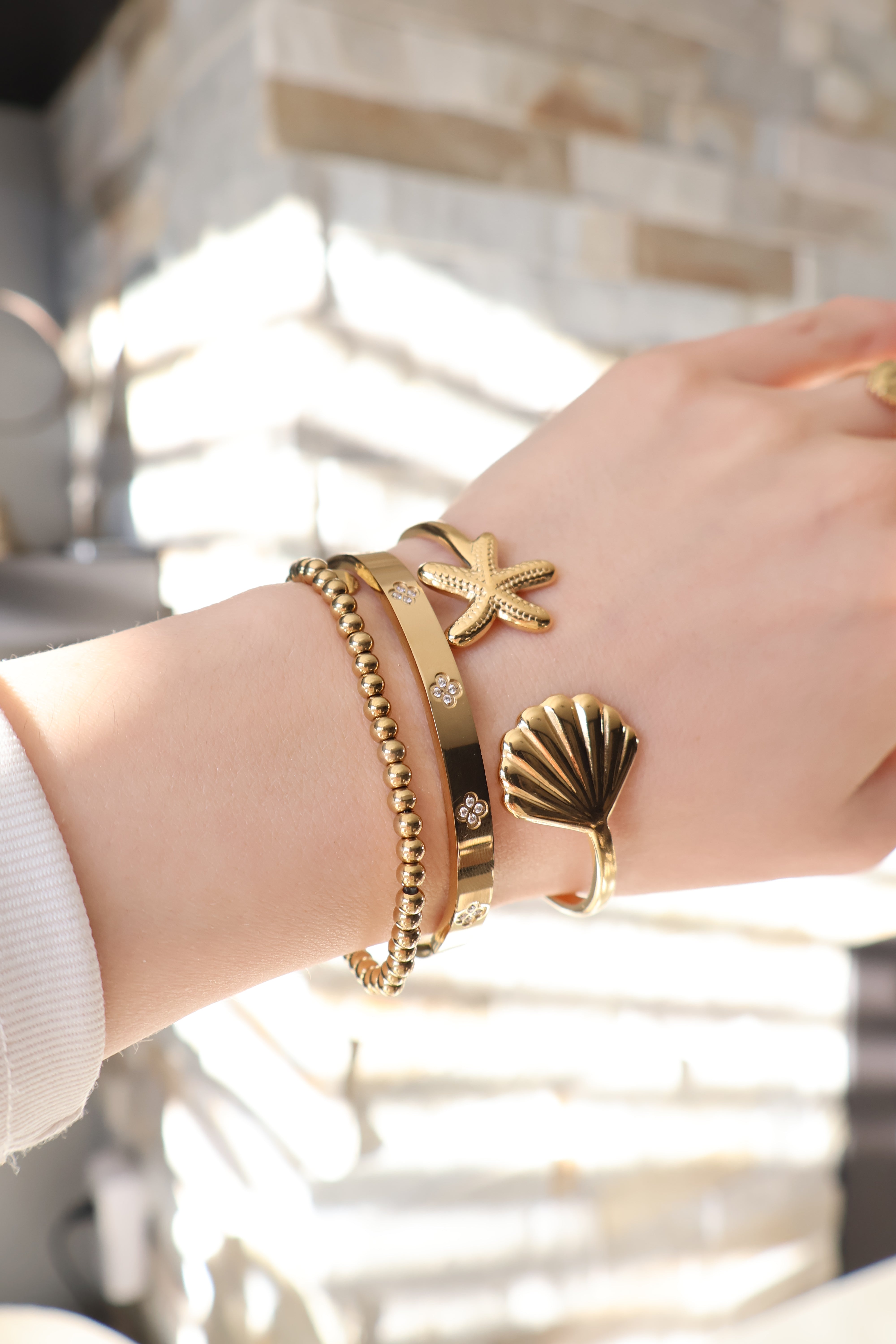 Gouden bangle met schelp en ster. Gemaakt van stainless steel dus is waterproof en hypo-allergeen.