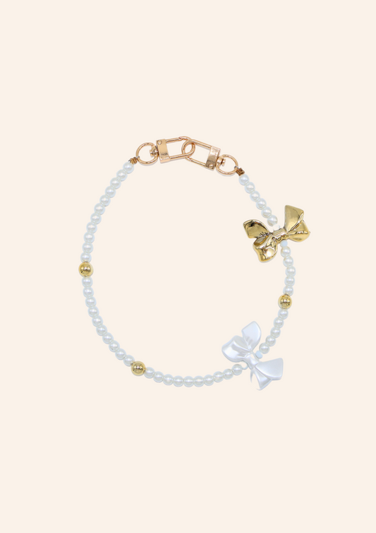 Tassenbedel met witte en gouden strikje om je tas te pimpen. Verkrijgbaar bij izzithelabel.nl als bagcharm.