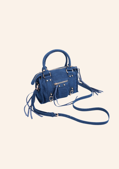 Donkerblauwe denim schoudertas met franjes en fringes. De tas heeft een vintage spijker look en heeft een ritssluiting. Wordt verkocht op izzithelabel.nl.