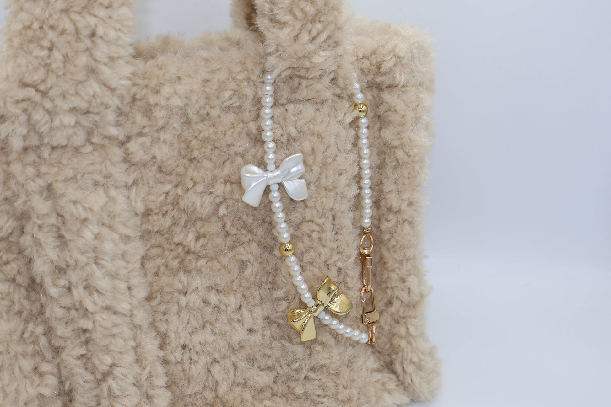 Tassenbedel met witte en gouden strikje om je tas te pimpen. Verkrijgbaar bij izzithelabel.nl als bagcharm.