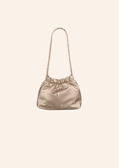 Champagne bruin kleurige schoudertas met hartjes studs. De tas heeft een leather look en heeft een druksluiting. Wordt verkocht op izzithelabel.nl.