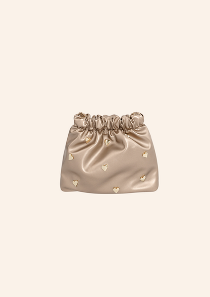 Champagne bruin kleurige schoudertas met hartjes studs. De tas heeft een leather look en heeft een druksluiting. Wordt verkocht op izzithelabel.nl.