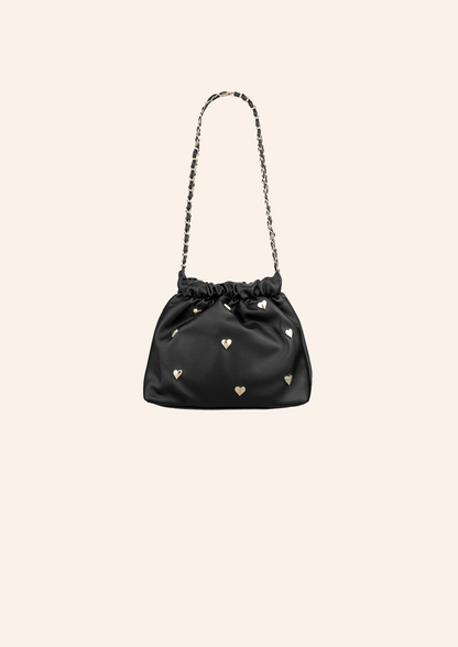Zwart kleurige schoudertas met hartjes studs. De tas heeft een leather look en heeft een druksluiting. Wordt verkocht op izzithelabel.nl.